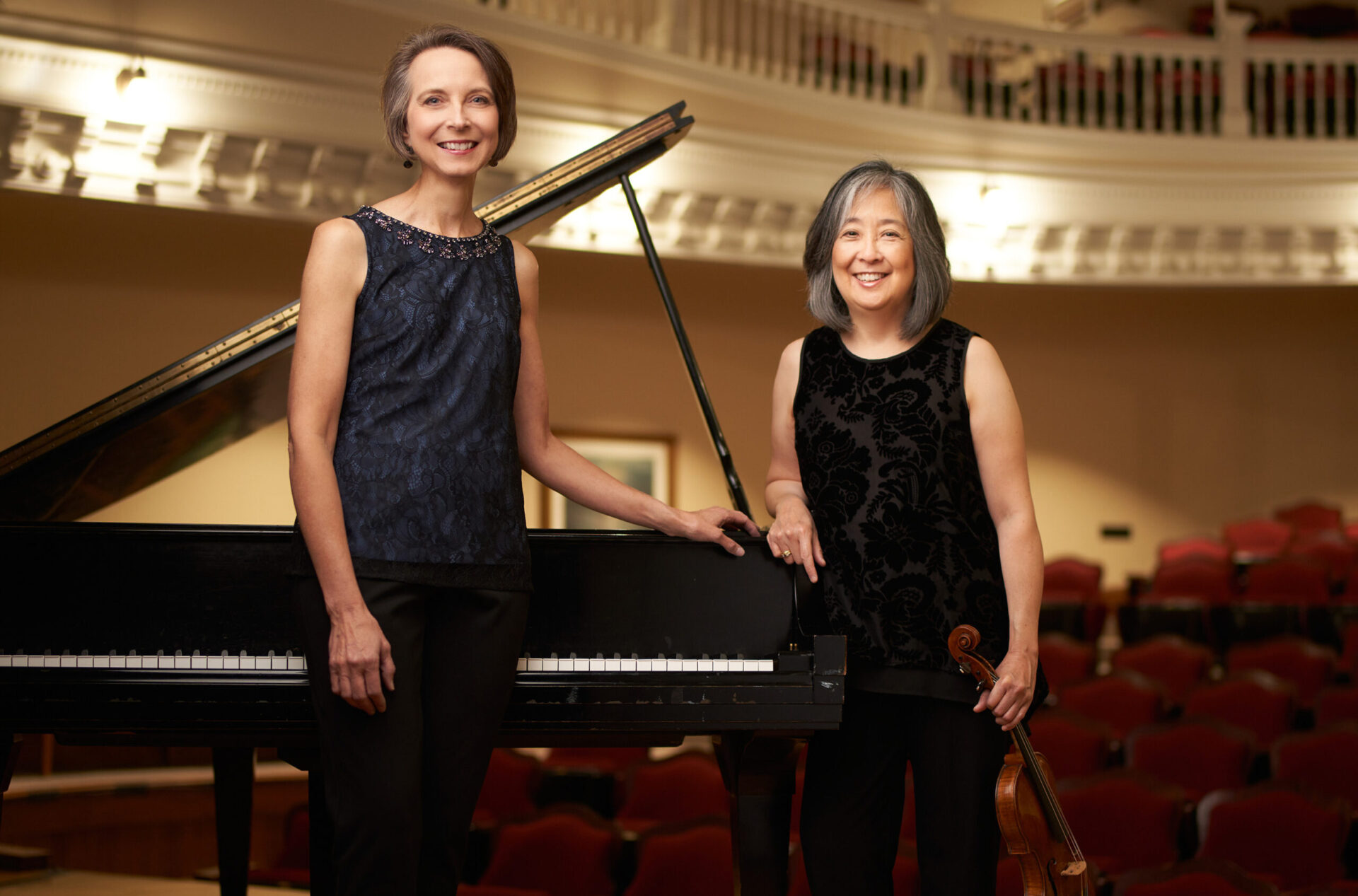 two women standing next to a piano
