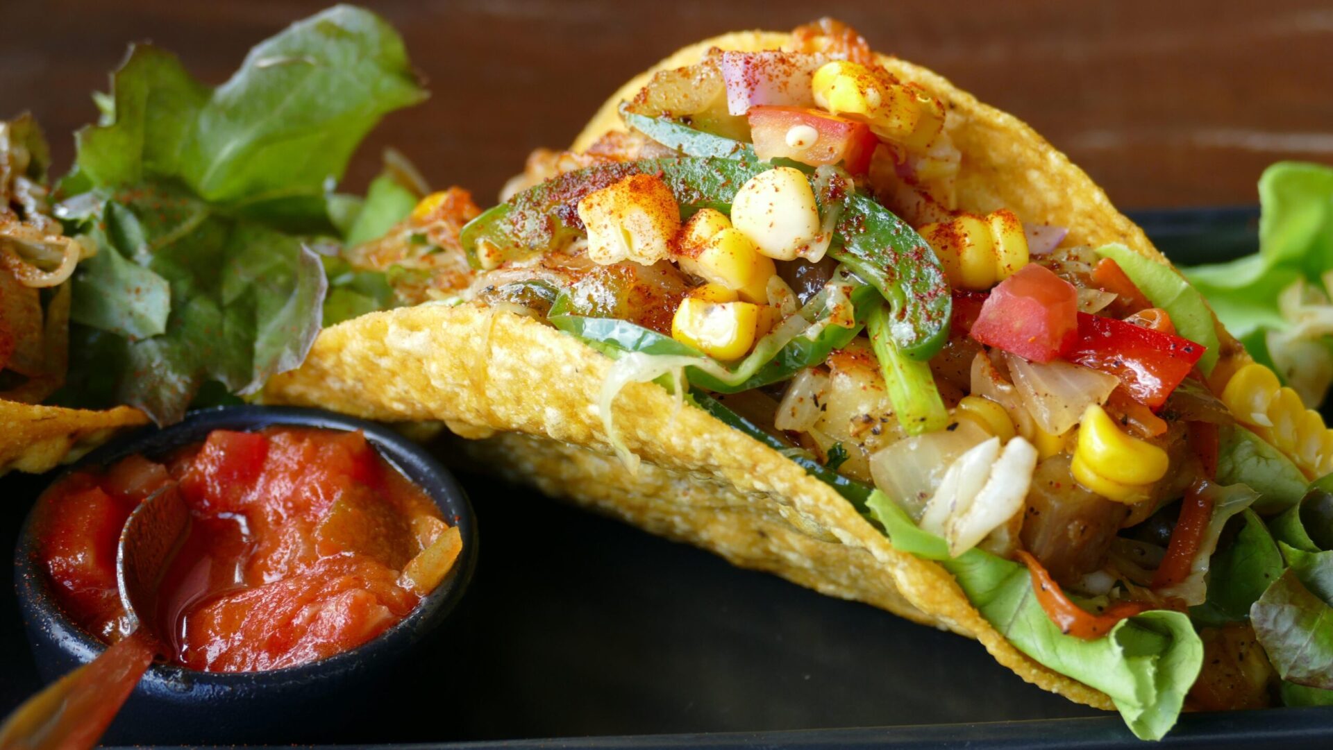 a taco with veggies and a small dish of salsa