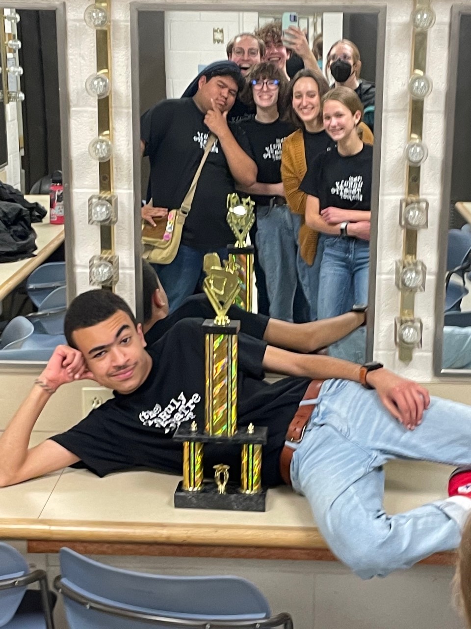 members of the Unruly Theatre Project taking a mirror selfie with a trophy