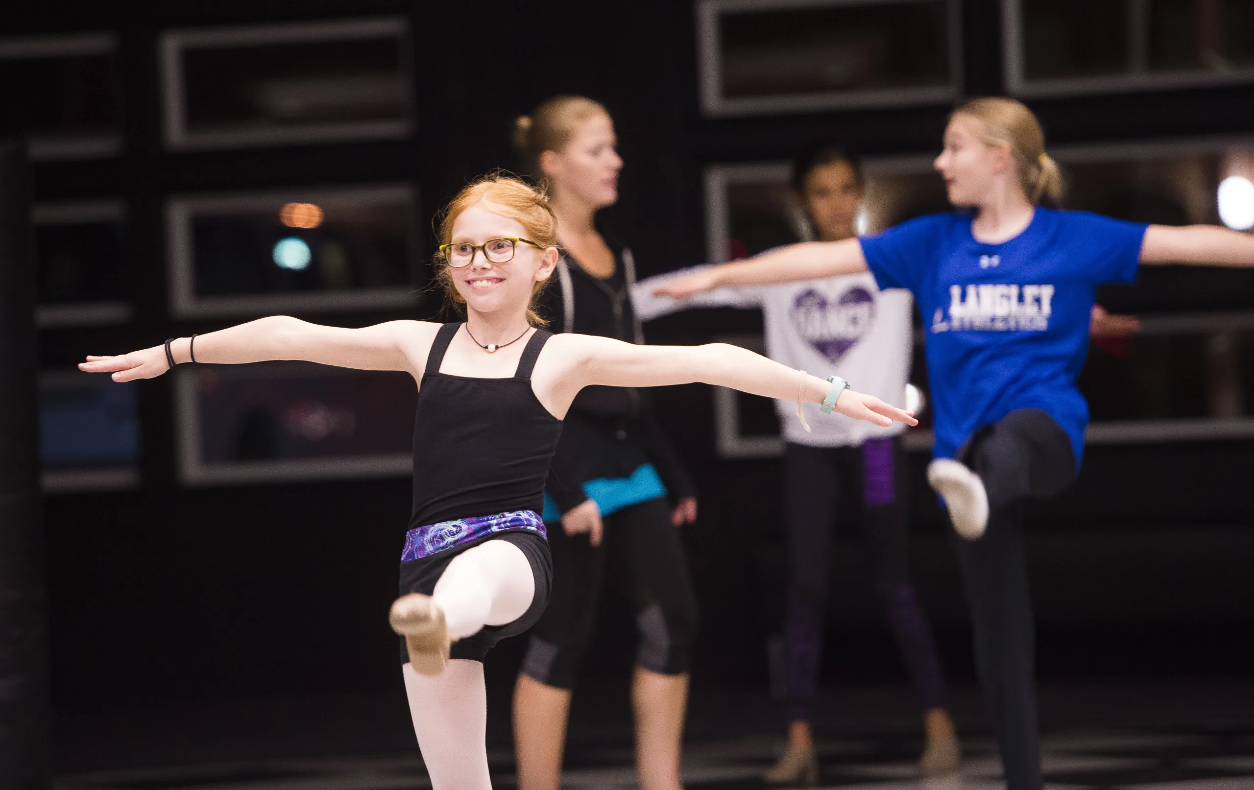 girl participating in a dance class with classmates behind her.