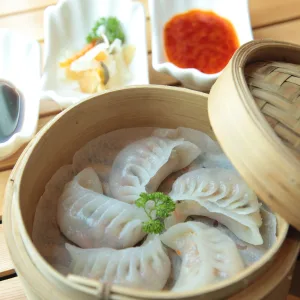 basket of dim sum with sauce dishes in the background.