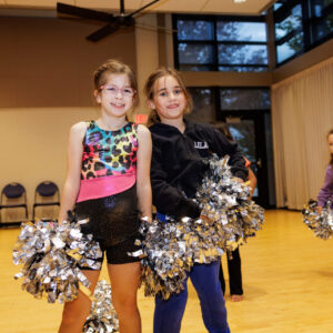 Two girls with pom poms in a cheerleading class.