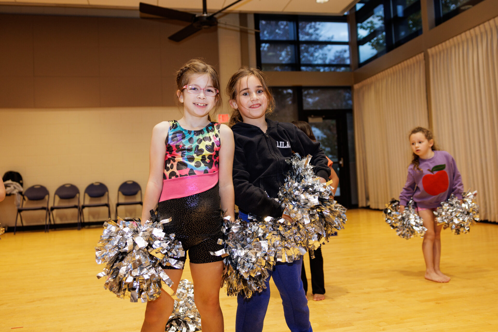 Two girls with pom poms in a cheerleading class.